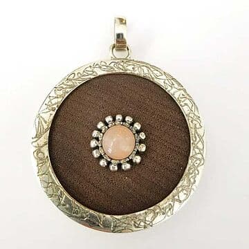 MEDALHA EM PAU SANTO, 4CM DE DIÂMETRO, DEBRUADA A PRATA COM PEDRA LUA ROSA E GRANITOS À VOLTA.